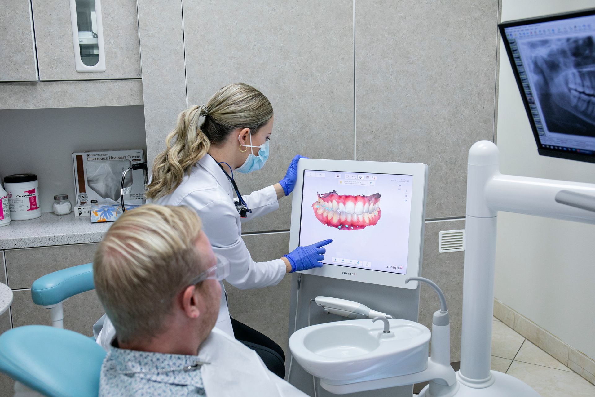 A dentist is looking at a patient 's teeth on a computer screen.