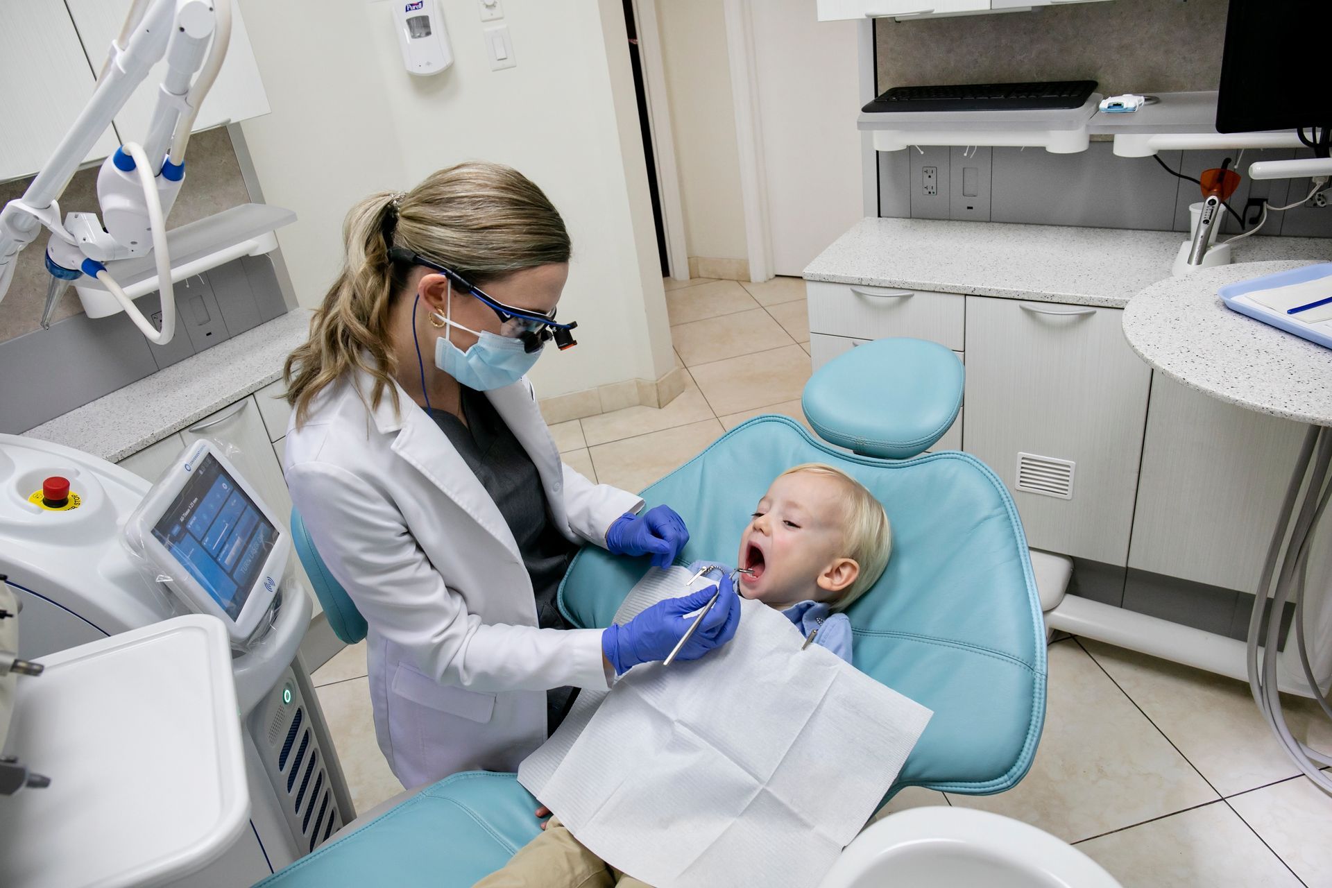 A dentist is examining a child 's teeth in a dental office.