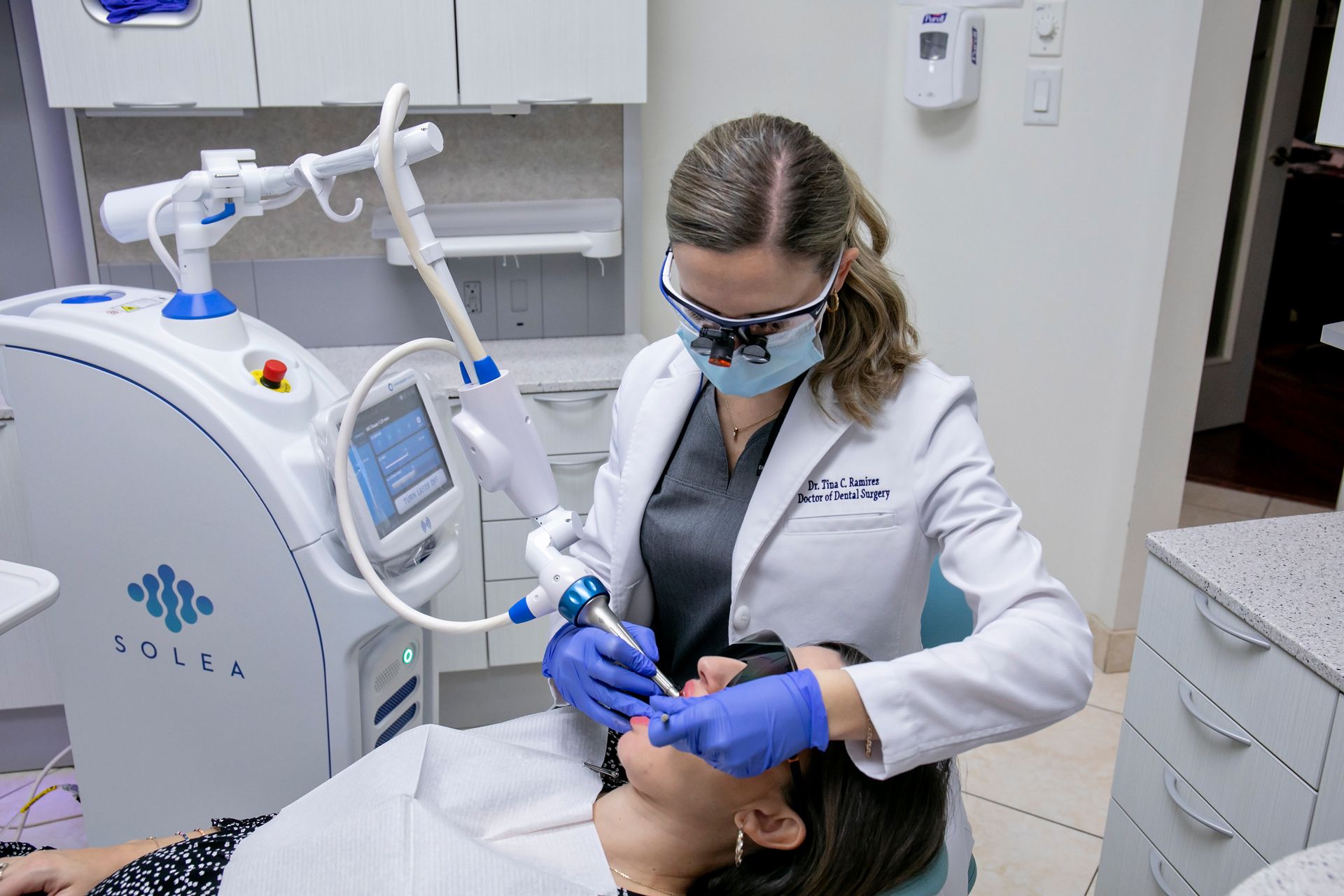 A woman is getting a laser treatment on her face in a dental office.