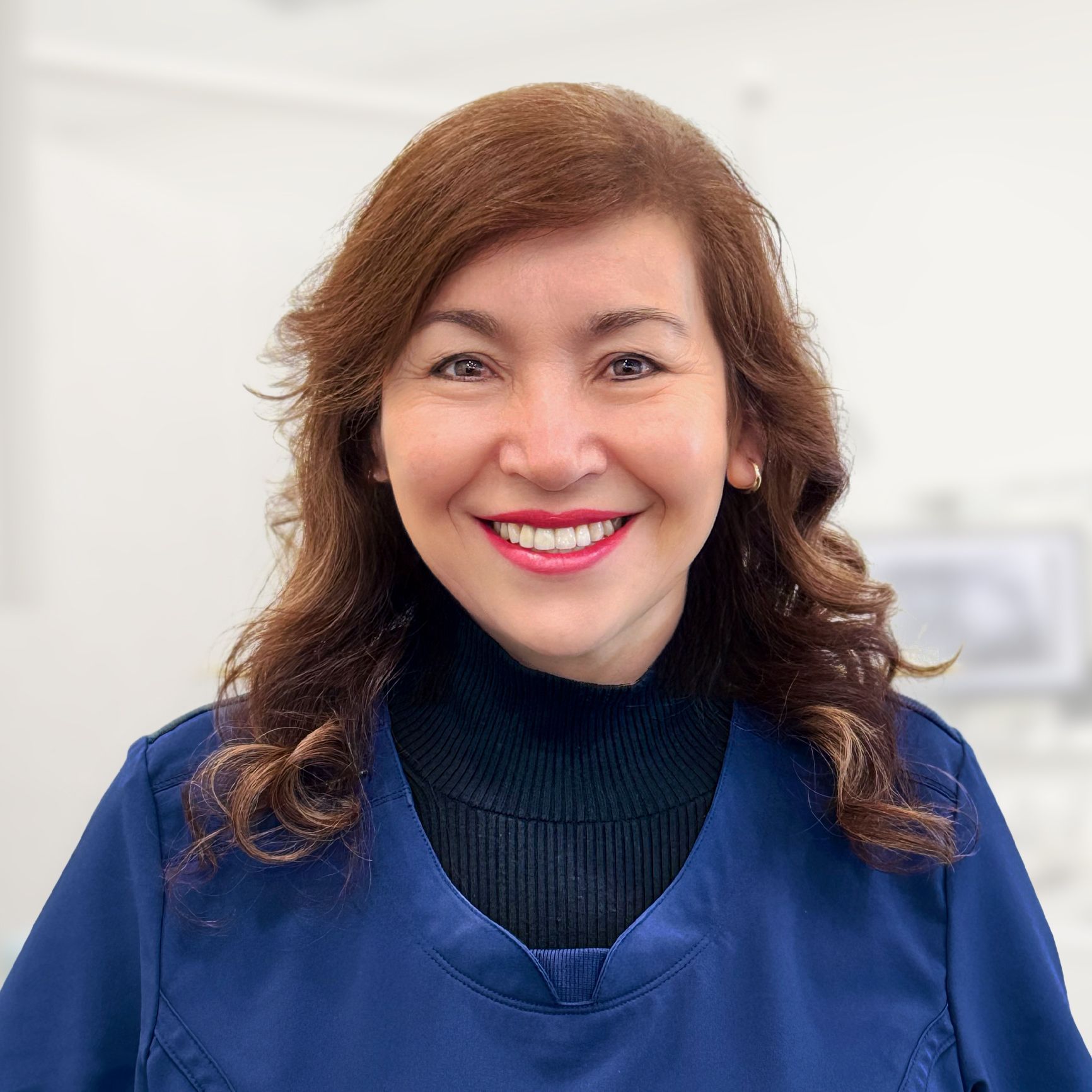 A woman in a blue scrub is smiling for the camera.