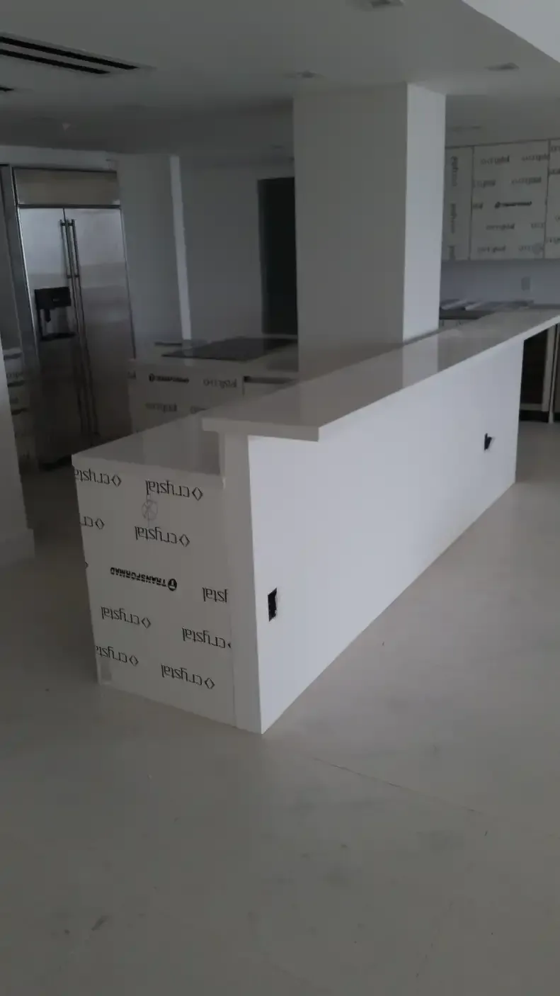 A long white counter in a kitchen with a lot of cabinets.