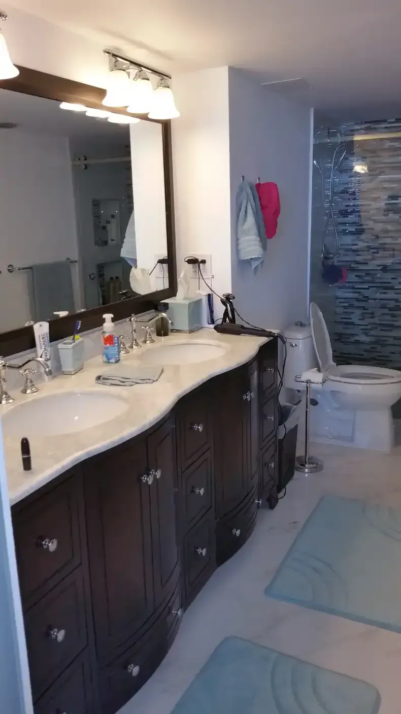 A bathroom with two sinks , a toilet , and a mirror.