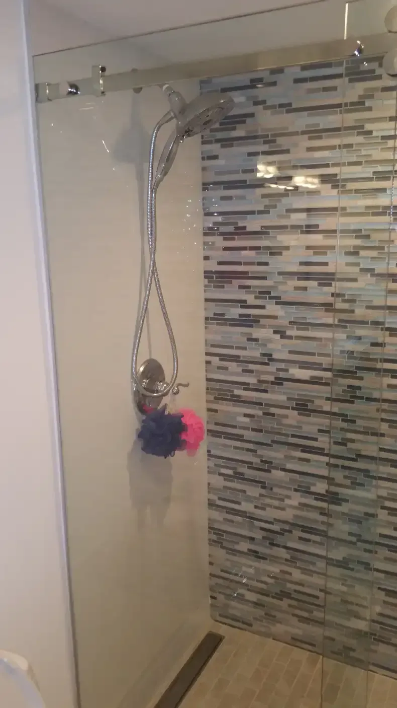 A shower with a sliding glass door and a stone wall.