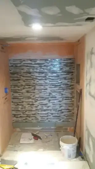 A bathroom under construction with a stone wall and a bucket of paint.