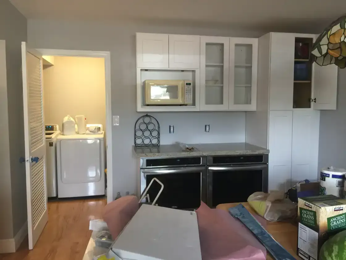 A kitchen with a washer and dryer and a microwave
