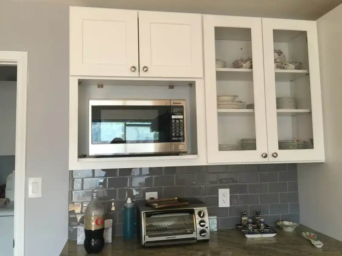 A kitchen with white cabinets and a toaster oven