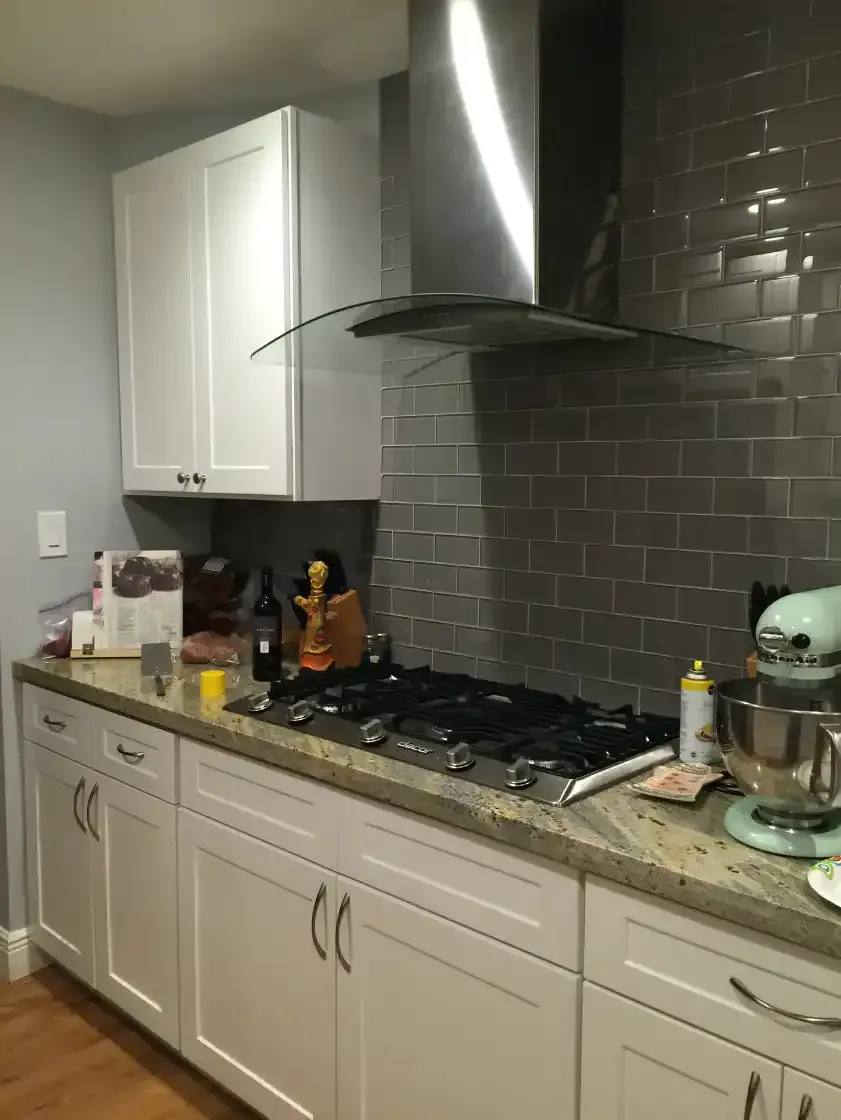 A kitchen with white cabinets and a stove top oven