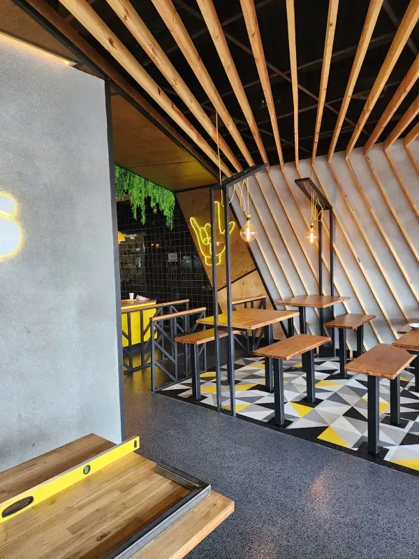 A restaurant with wooden tables and benches and a yellow level on the floor