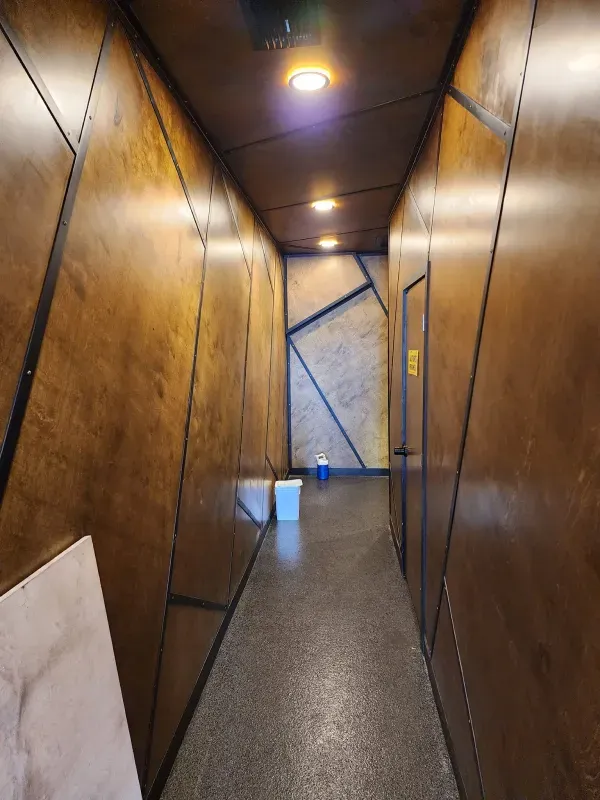 A long hallway with wooden walls and a concrete floor