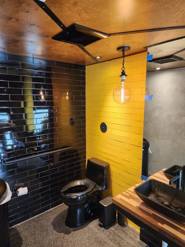 A bathroom with a black toilet and yellow walls