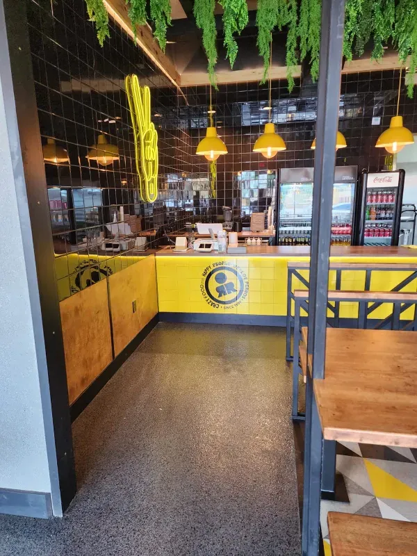 The inside of a restaurant with a yellow counter and tables