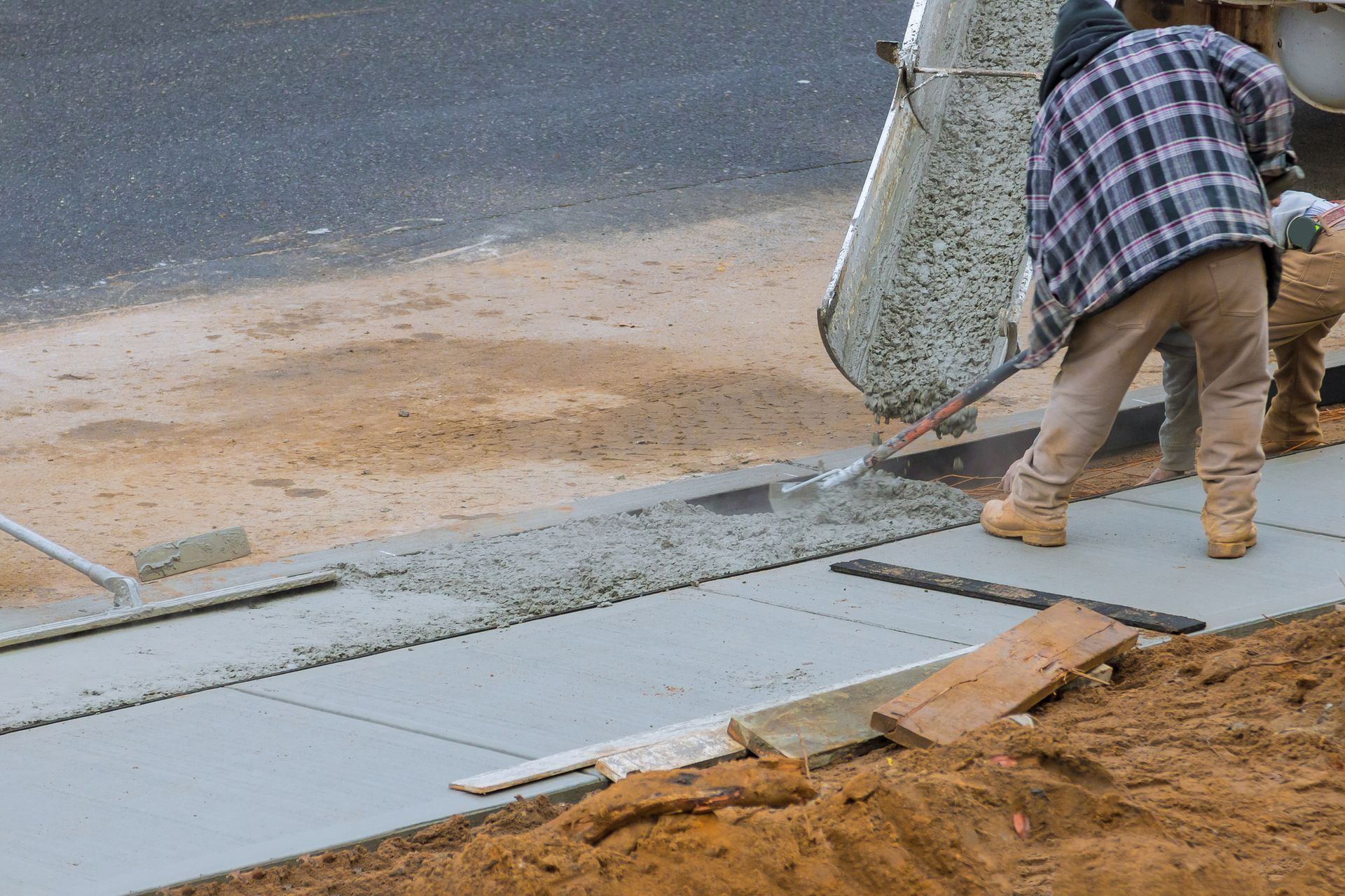 A Man Is Pouring Concrete Onto A Sidewalk - Columbus, IN - Orville K. Fleetwood Asphalt