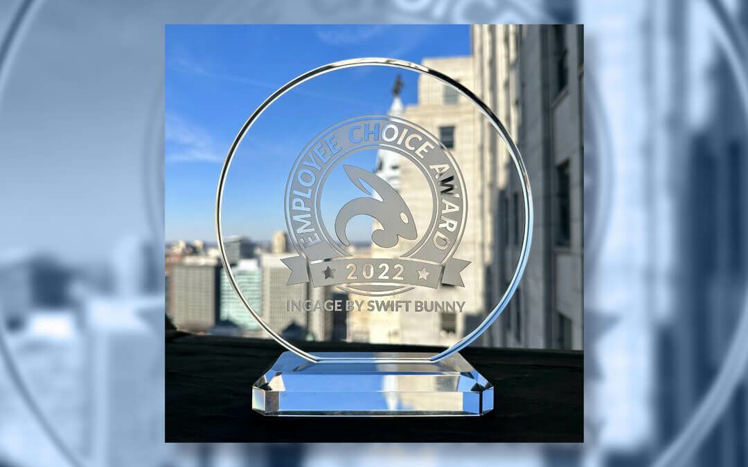 Clear glass employee choice award with a bunny logo, against a city backdrop.