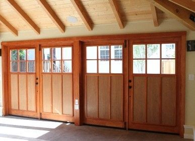 Four wooden doors with glass upper panels and wooden lower panels, installed in a room with a wood-paneled ceiling.
