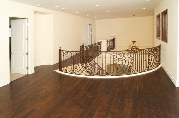 A dimly lit bedroom with a round bed, vanity, and artwork, overlooking city lights through the windows.