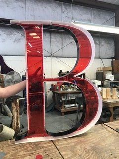 A large red letter b is sitting on top of a wooden table.
