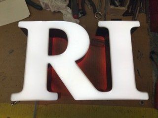 A white letter r is sitting on a wooden table