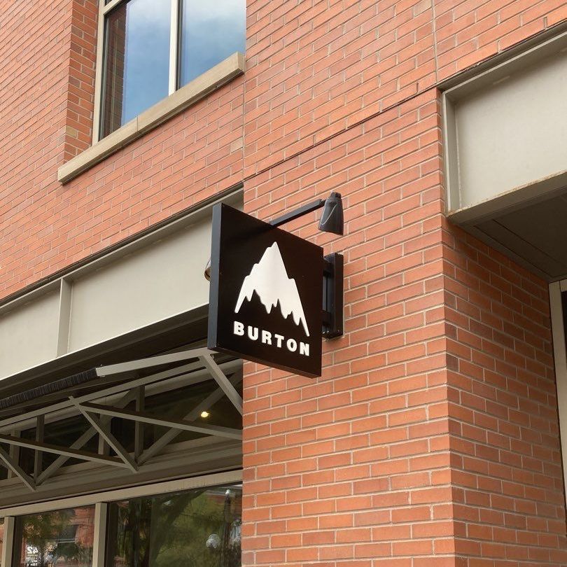 A burton sign hangs from the side of a brick building