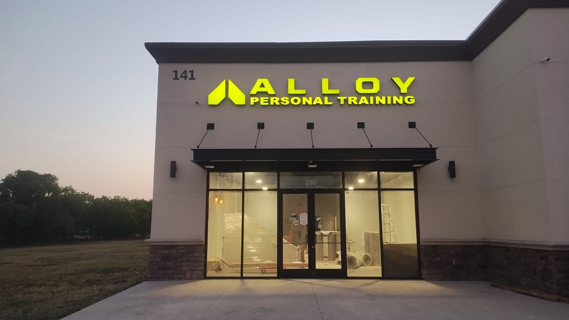 Retail storefronts under construction with workers in safety vests.