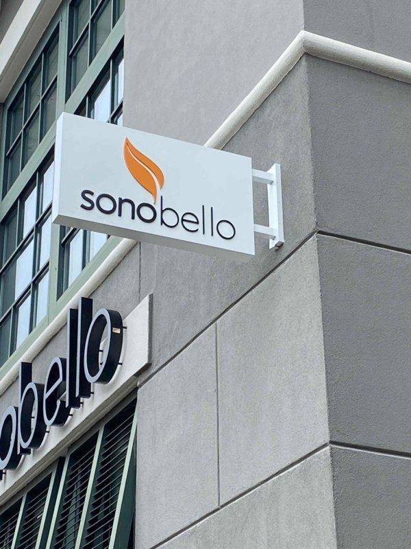 A sonobello sign hangs from the side of a building