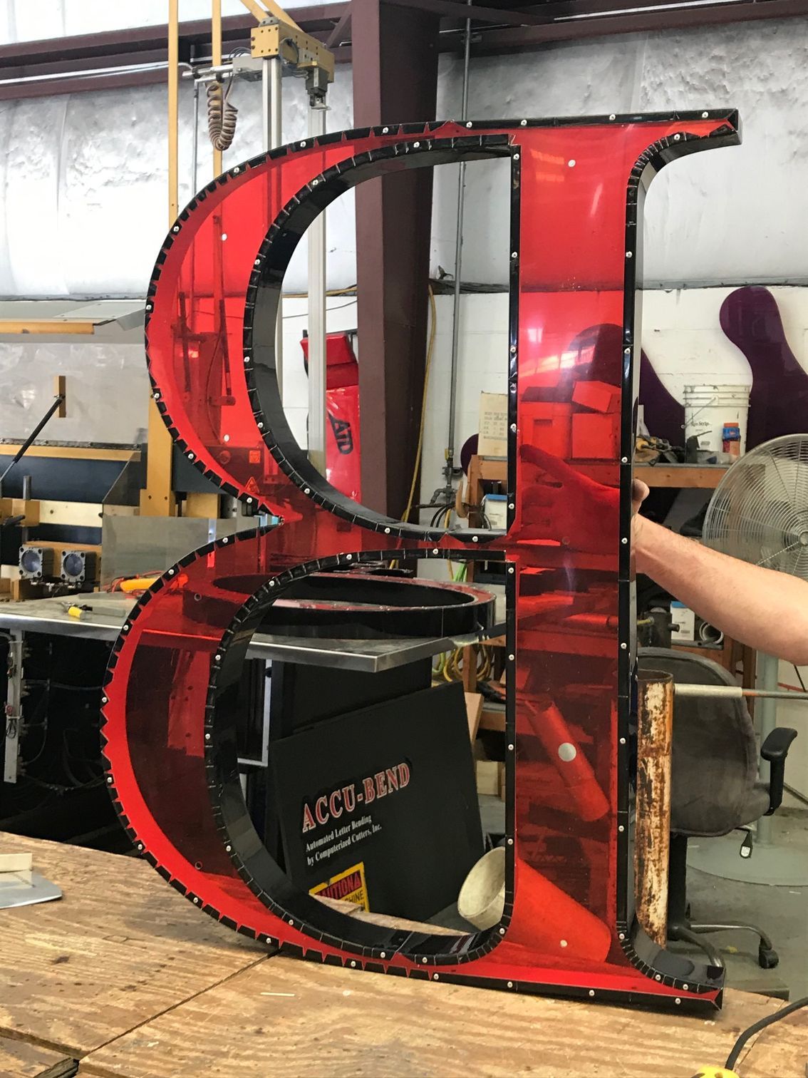 A large red letter b is sitting on a wooden table.