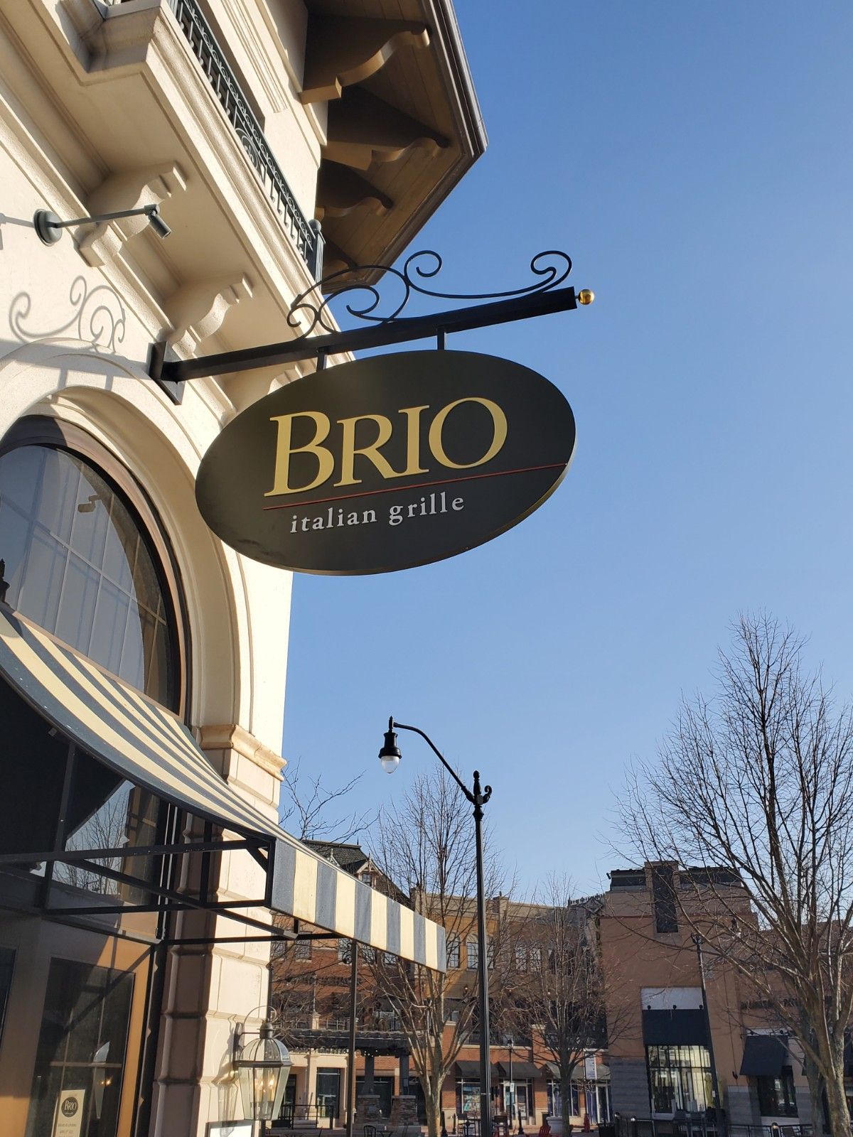 A sign for brio italian grille hangs from the side of a building.