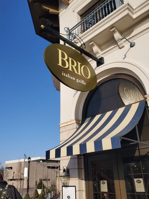 A sign for brio italian grills hangs from the side of a building