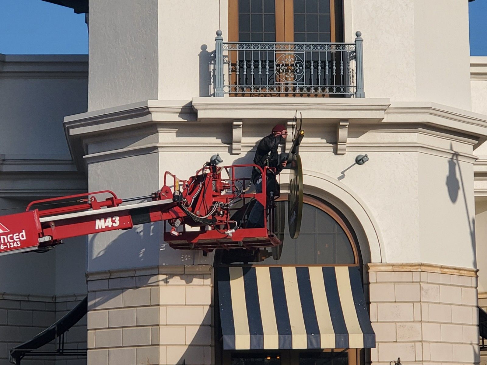 A man is using a crane to remove a sign from a building