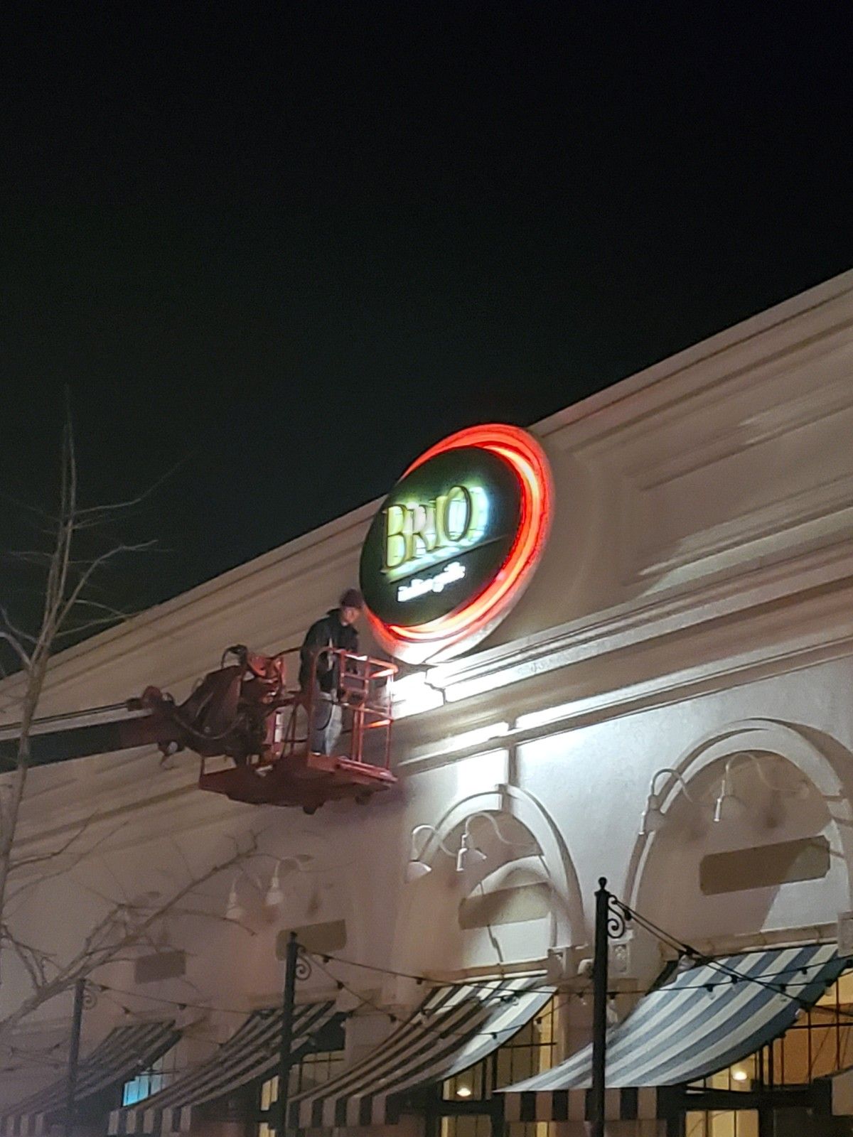 A man is working on a sign on the side of a building at night.