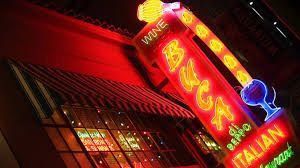 A neon sign for a wine and italian restaurant is lit up at night.