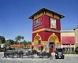 A car is parked in front of a sandwich shop.