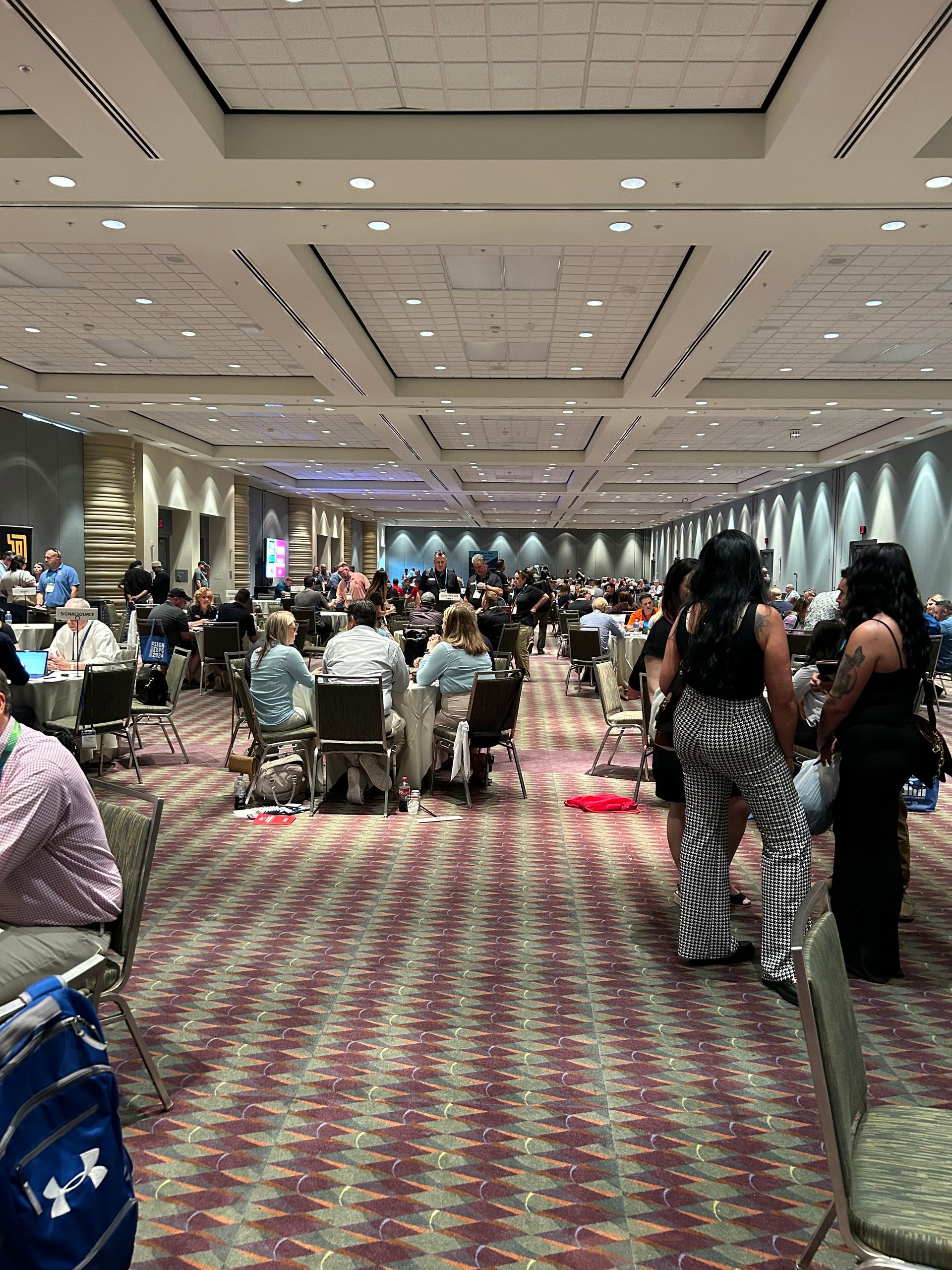 A large room filled with people sitting at tables and chairs.