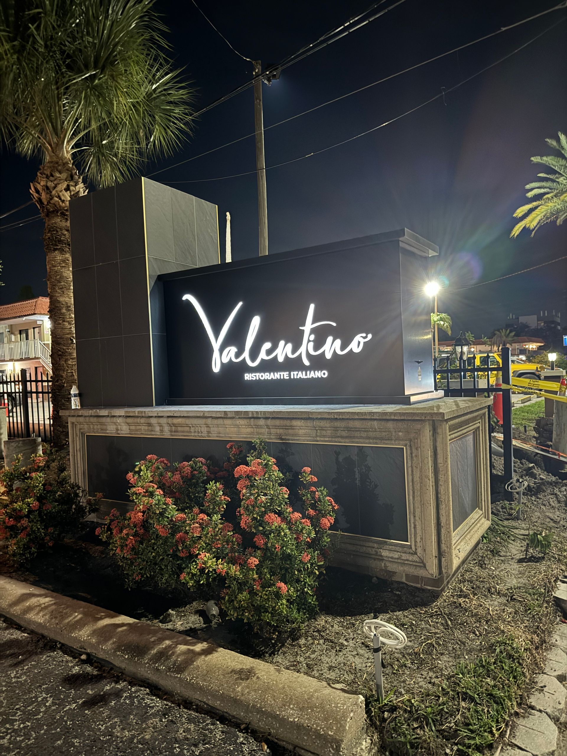 A sign for a restaurant called valentino is lit up at night.