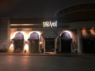 A restaurant called bravo is lit up at night