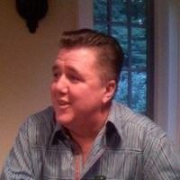 A young man wearing a white shirt and tie is smiling for the camera.