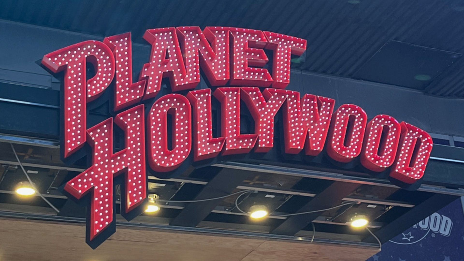 A sign for planet hollywood is lit up at night