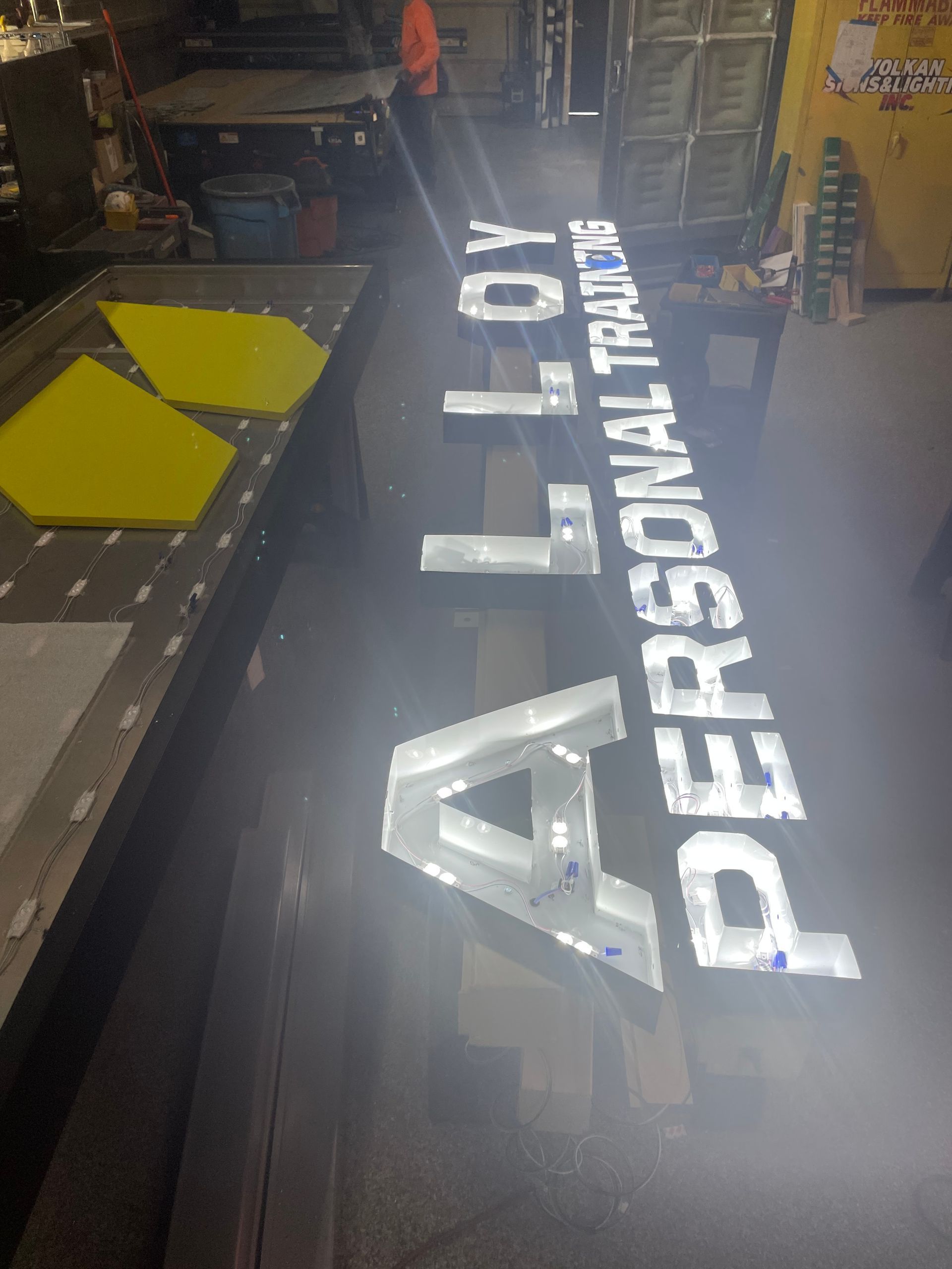 A sign for a personal trainer is lit up in a dark room.