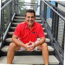 A man in a red usa shirt sits on a set of stairs