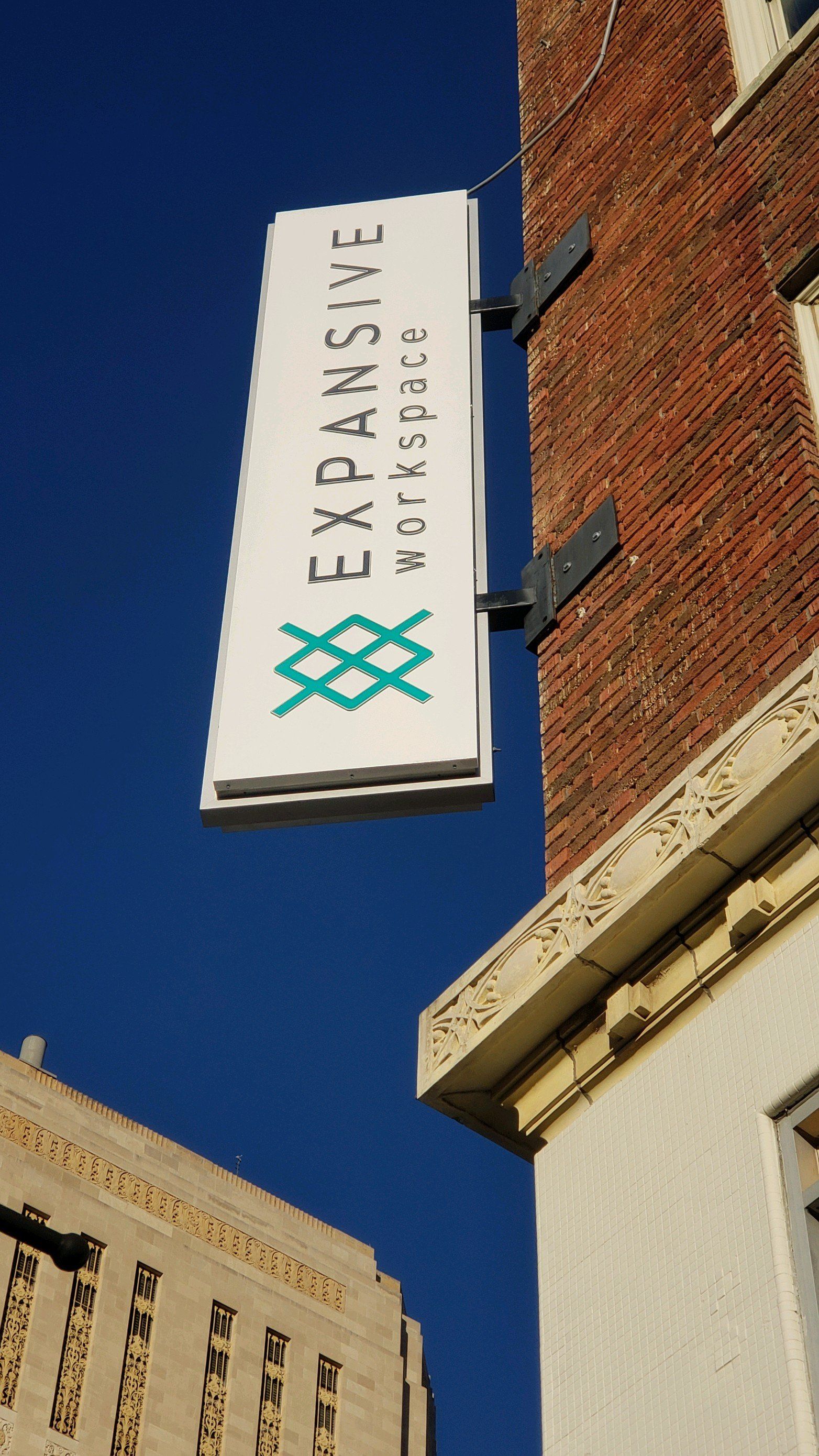 A white sign on the side of a brick building says expansive workspaces.