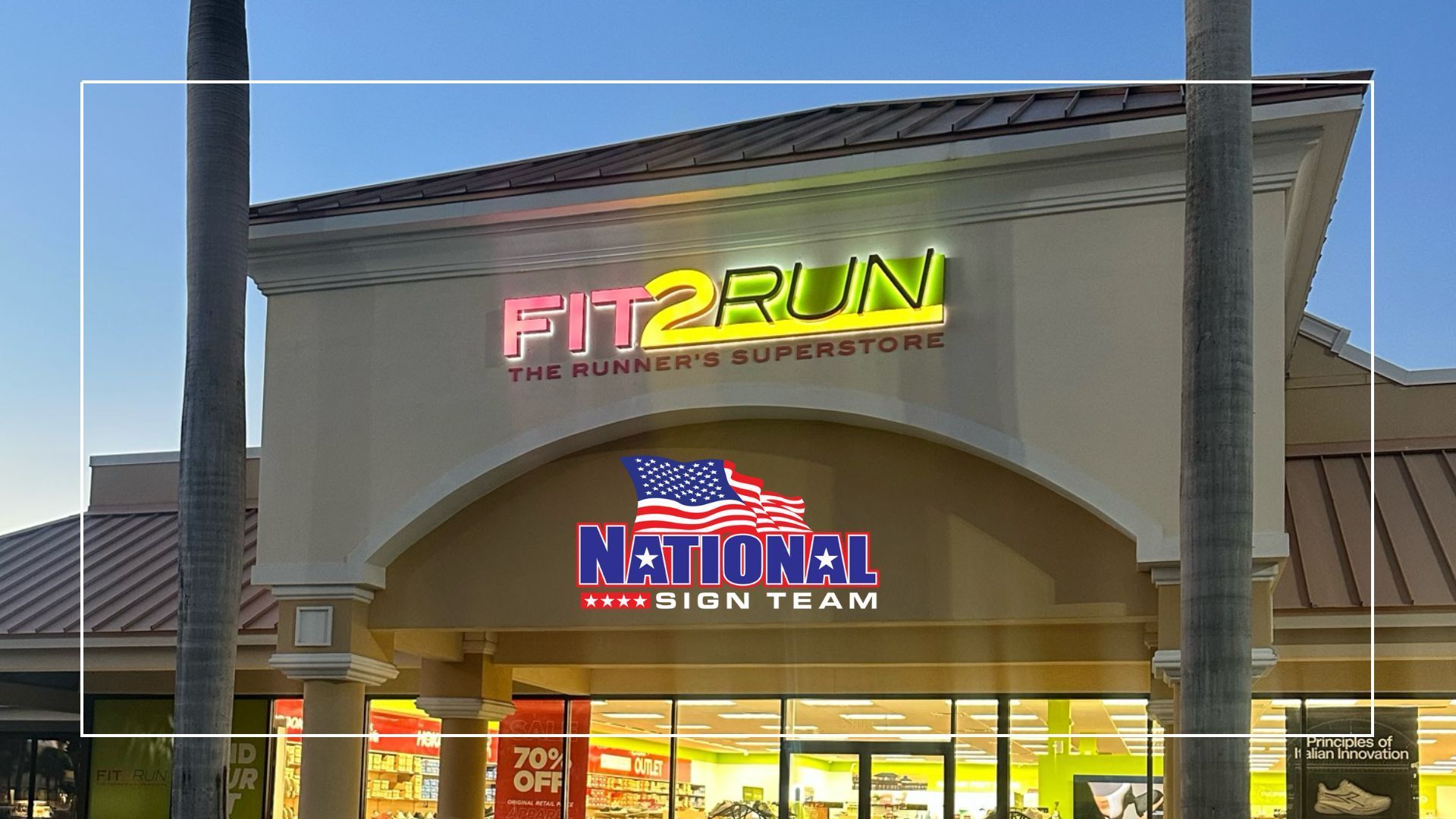 Fit2Run store front with neon sign and National Sign Team logo at dusk.