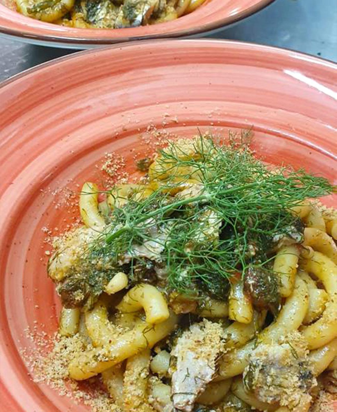 Un primo piano di un piatto di pasta con aneto sopra.