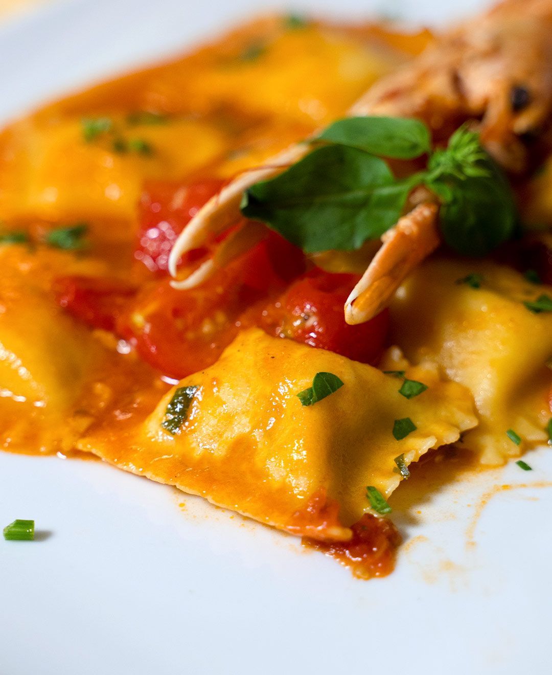 Un primo piano di un piatto di ravioli con gamberi e pomodori su un tavolo.