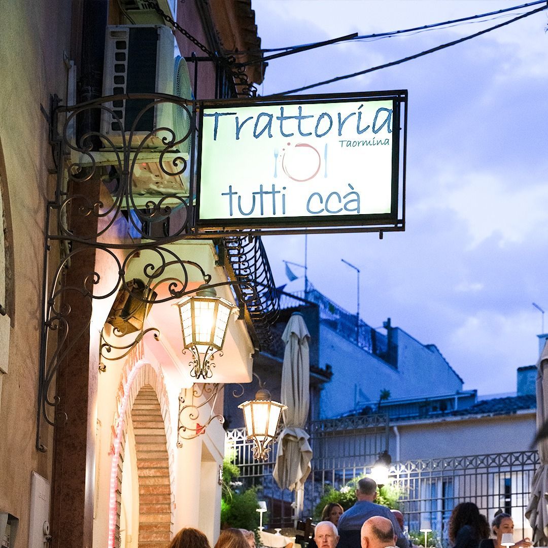 Un cartello per trattoria tutti coa è appeso al lato di un edificio