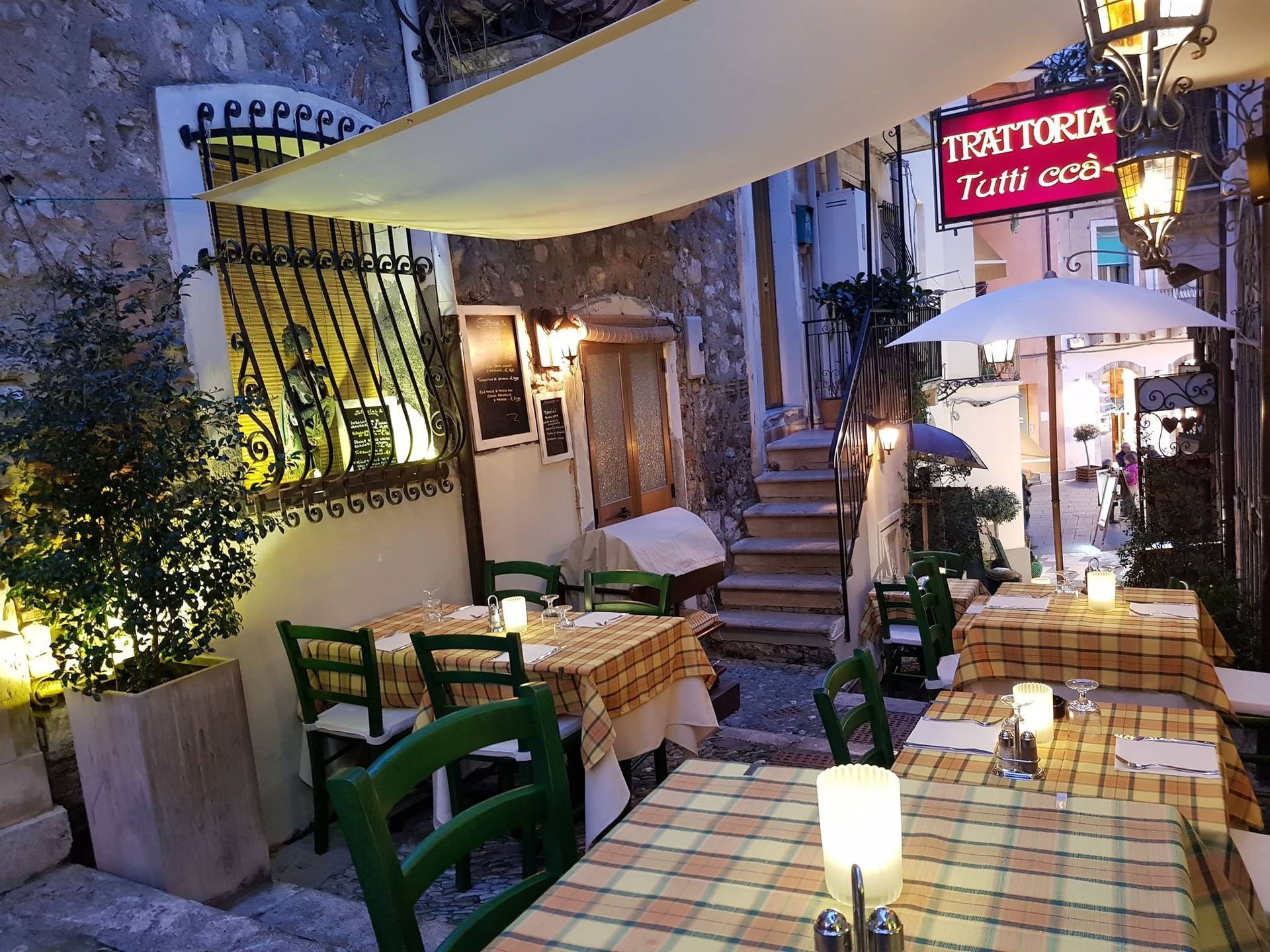 Tavoli e sedie fuori da un ristorante con un cartello che dice trattoria