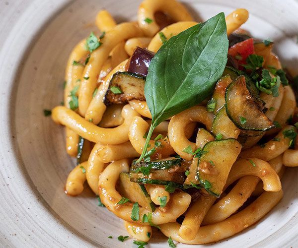 Un primo piano di un piatto di pasta con sopra delle verdure