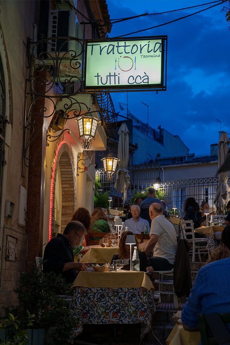 Un gruppo di persone è seduto ai tavoli fuori da un ristorante.
