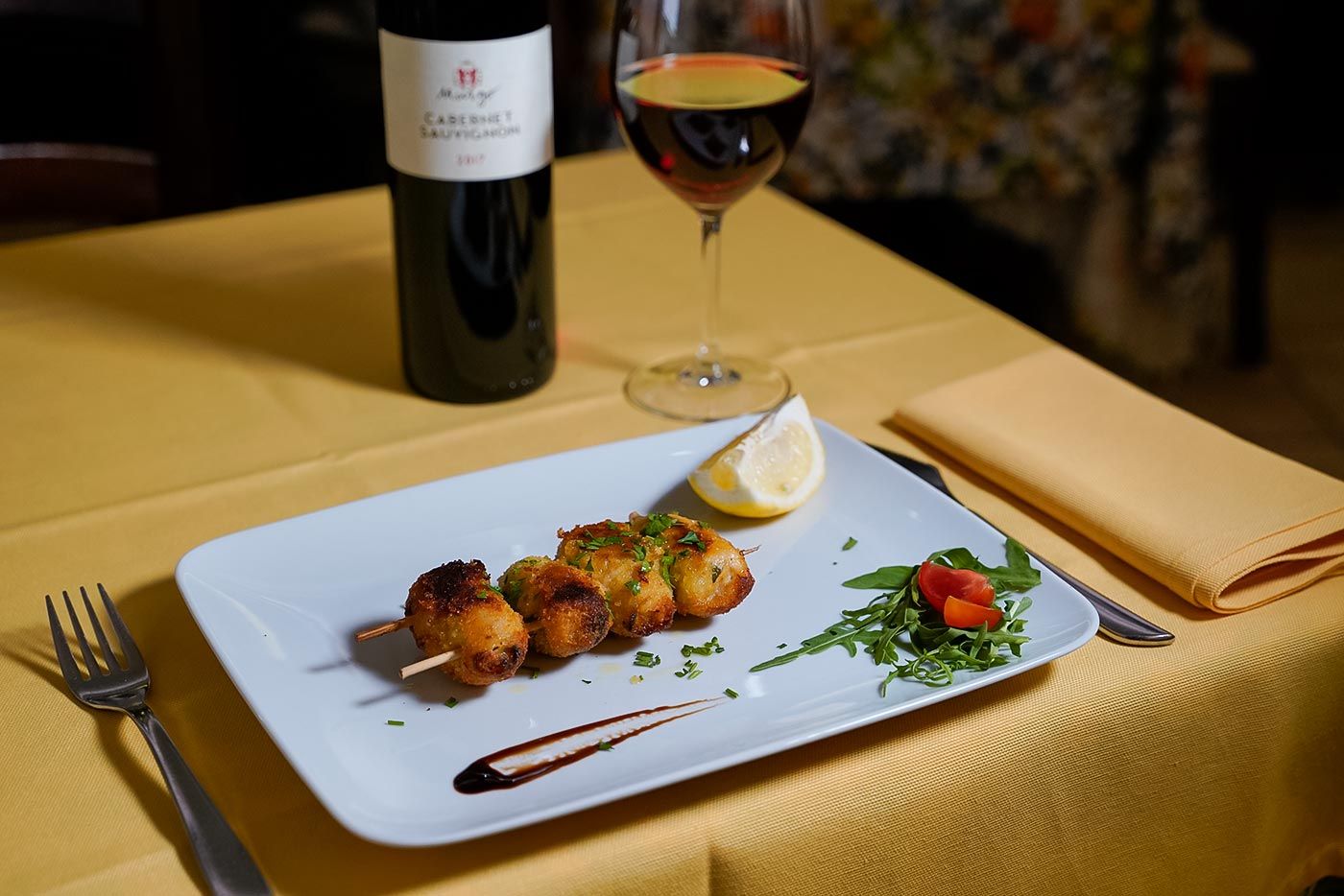 Una bottiglia di vino è appoggiata accanto a un piatto di cibo su un tavolo