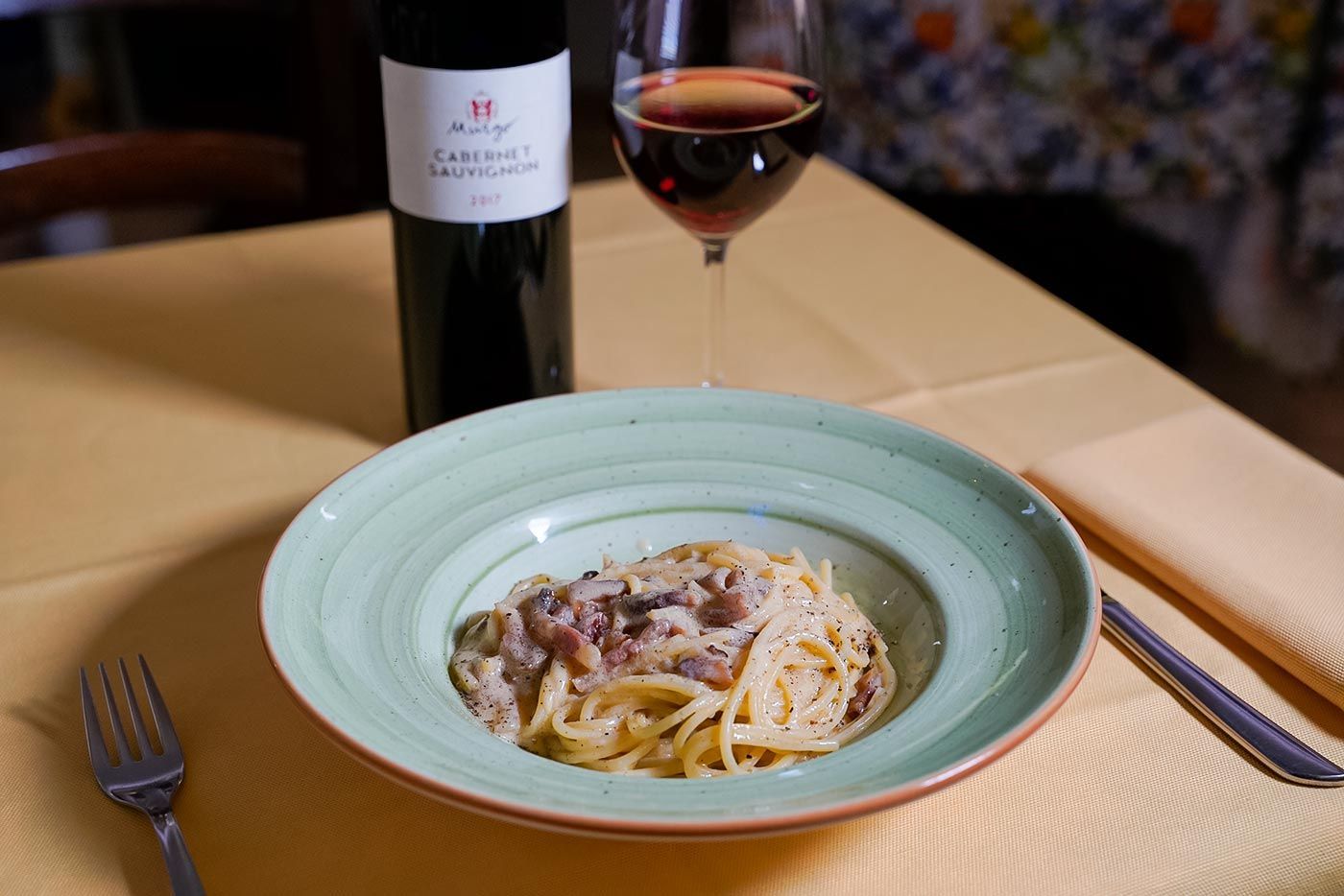 Un piatto di spaghetti e un bicchiere di vino su un tavolo.