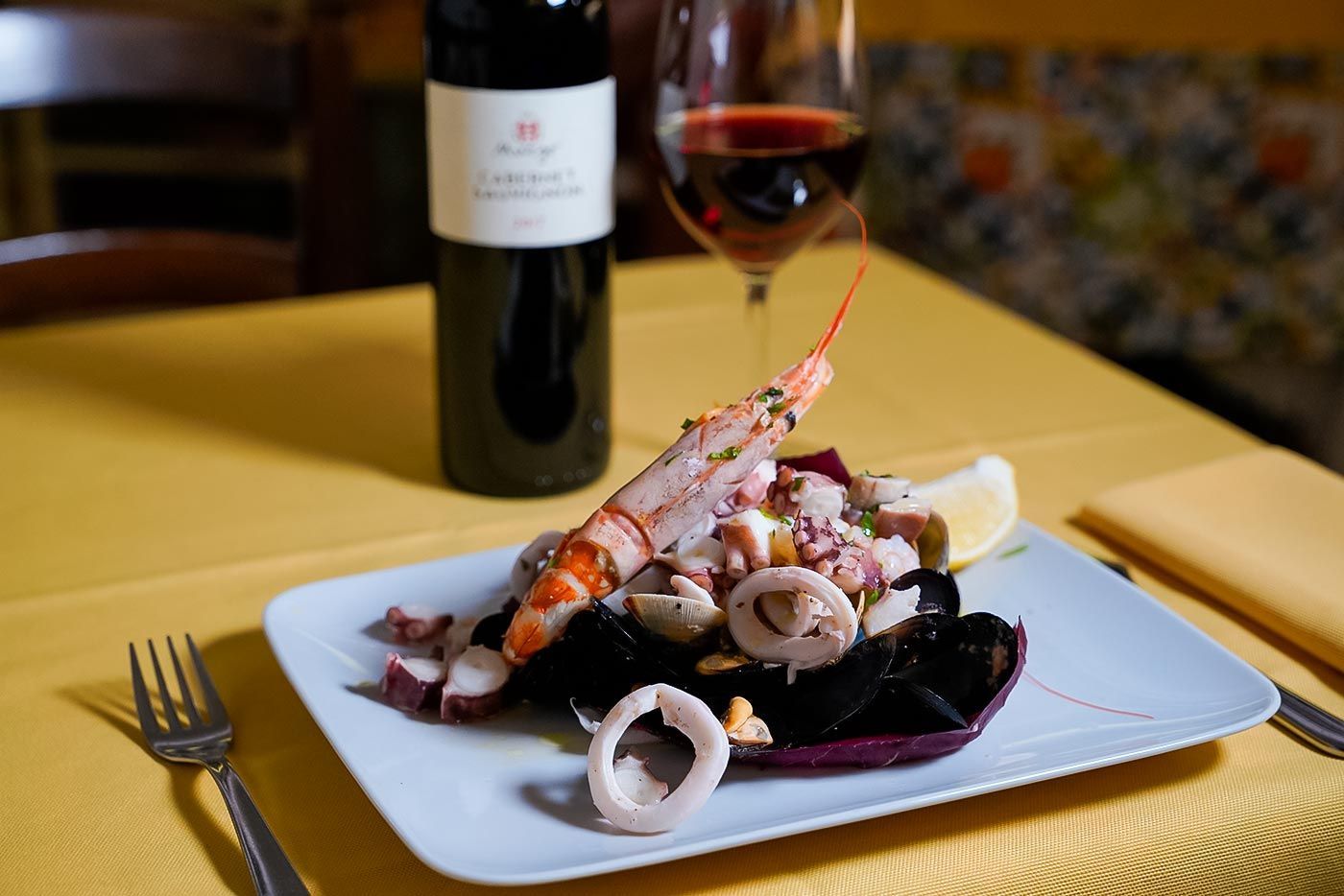 Un piatto di cibo e un bicchiere di vino su un tavolo.