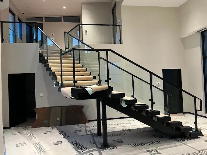 Modern interior staircase with black railings and beige carpeted steps in a bright lobby area